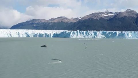Drone tracks kitesurfer below Perito Moreno Glacier with support boat on Lago 库存影片 341341682