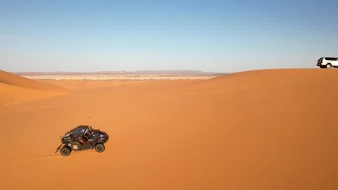 Drone tracks side-by-side UTV driving across Erg Chebbi dunes near Merzouga Stock Footage 339755520
