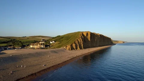 Drone tracks sideways with the beach and cliffs in West Bay Stock Footage 94363670