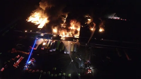 Drone turning around devastating scene of recycling plant on fire at night Stock Footage 92644232