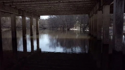 Drone Under Bridge with Creek Reverse Stock Footage 99607484