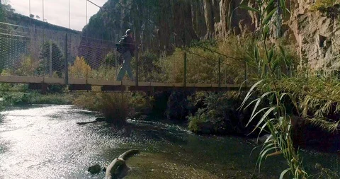 Drone upward flight and elderly walker crosses a suspension bridge Stock Footage 124387781