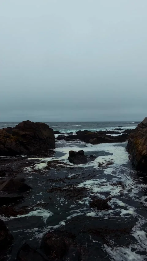 Drone Vertical Forward Flight Over a Rocky Ocean Shoreline Under a Cloudy S.. Stock Footage 339252232