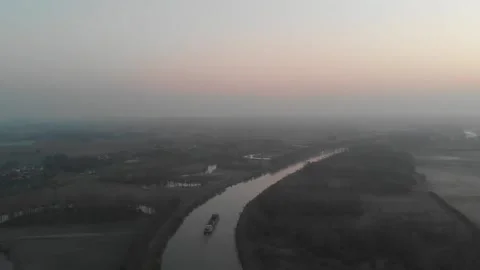 Drone video of a boat on a river going towards a misty valley Stock Footage 208641063