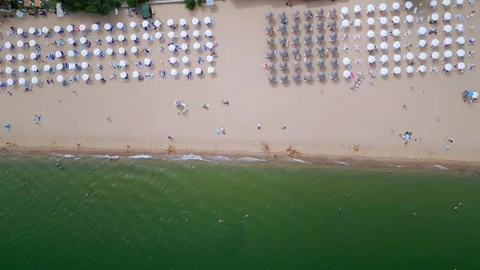 Drone video capturing a top-down view of a beach with rows of colorful umbrellas Video stock 281992553