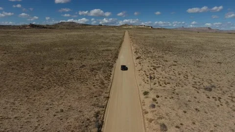 Drone video of car driving down straight dirt road in desert Stockbeeldmateriaal 148599908