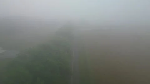 Drone video of a car driving down a foggy blacktop road Stock Footage 246322952