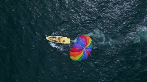 Drone video of a colorful parasail being towed by a speedboat over the ocean Stock Footage 281982653