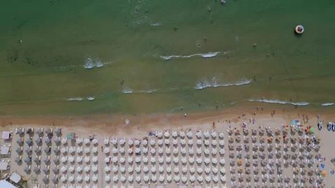 Drone video of a crowded beach with rows of umbrellas and sunbathers, set Stock Footage 281965035
