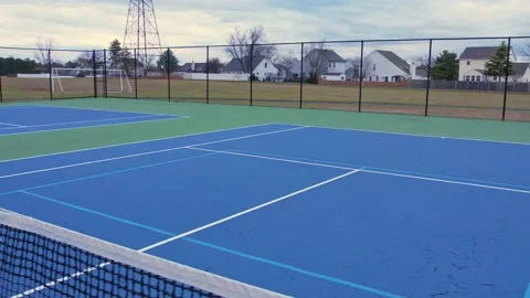 Drone video of an empty blue and green tennis court in a residential area Stock Footage 231045261