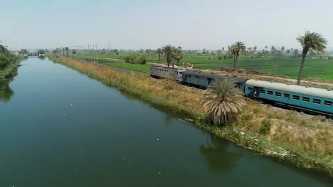 Drone video of a moving Egyptian train next to a canal Stock Footage 175599605