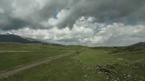 Drone video. Old road and highway, green hills, power lines, snowy mountains. Stock Footage 252012262