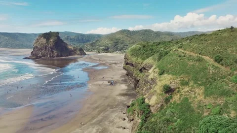 Drone video of Piha beach, with distant figures enjoying the sand and surf Stock Footage 231114087