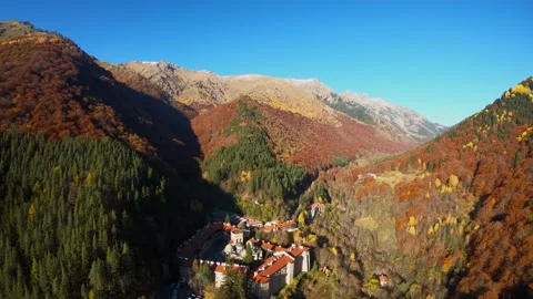 Drone video pulling away from Rila Monastery over autumn mountain forest Stock Footage 320387669