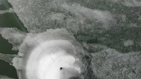 Drone video rotation over crazy patterns in ice on frozen lake with green wa Stockbeeldmateriaal 148015983