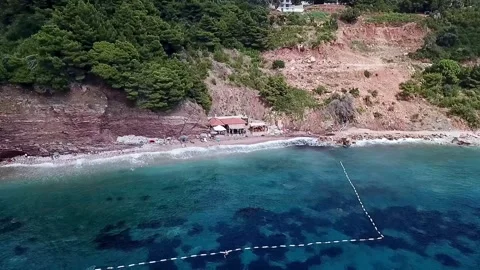 A drone video of a small beach bar and the beach in Sveti Stefan Montenegro Stock Footage 315679088