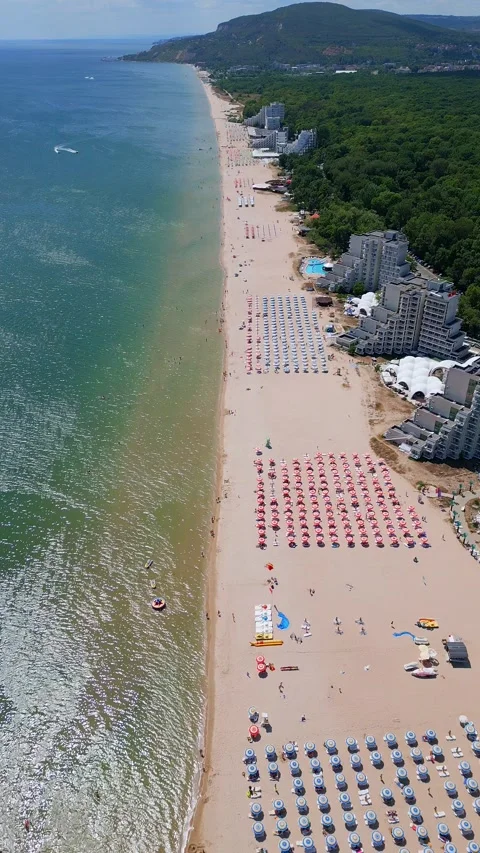 Drone video of a sprawling beach with rows of umbrellas, sunbathers, and water Stock Footage 281990854
