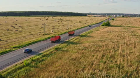 Drone Video - Tracking Shot of Two orange dump trucks haul sand along a road Stock Footage 172545334