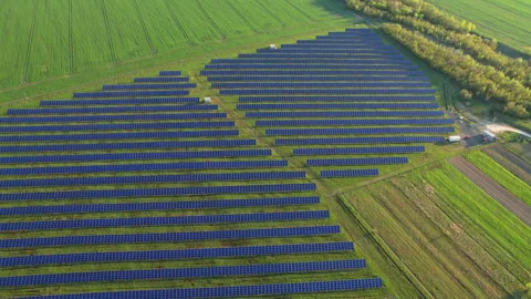 Drone video of utility scale solar farm across green, brown agricultural plots Stock Footage 346545423
