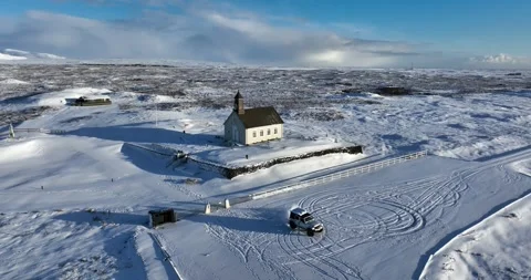 Drone view of a 4x4 drifting across snowy ground near Strandarkirkja church in 库存影片 335138541