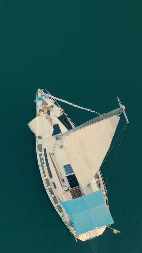 Drone view from above shows couple lying relaxed on a yacht, floating on calm Stock Footage 313755935
