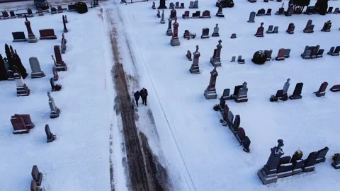 Drone view above two people walking in cemetery in winter HD Stock Footage 204822727