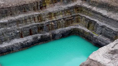Drone view across turquoise quarry water bordered by steep layered limestone Stock Footage 341096357