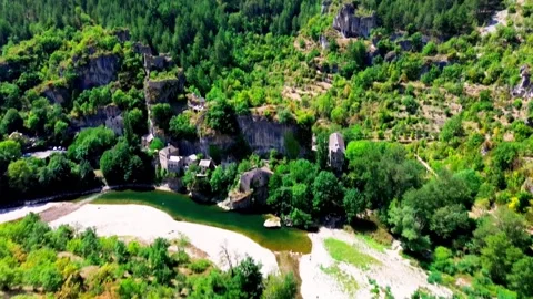 Drone View of Ancient Stone Village on Riverbank Surrounded by Forested Cliffs Stock Footage 316609652