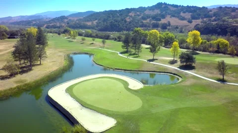 Drone view of beautiful golf course by pond and mountains Stock Footage