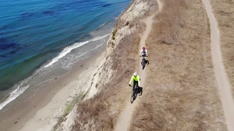 Drone view of bicycles ridden along beachside cliff Stock Footage 149384439