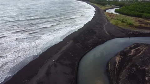 Drone view of a black volcanic sand beach and river mouth on the coast of E.. Видео 341312963