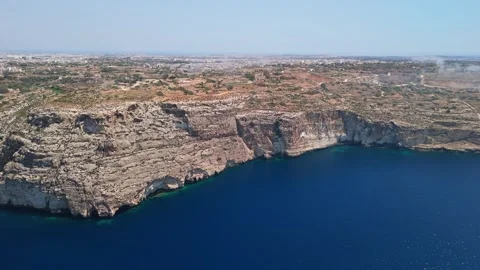 Drone view of Blue Grotto cliffs rising over clear water on Malta's coast Stock Footage 337002523
