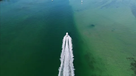Drone view of boat moving forward and leaving foamy wake that contrasting with Stock Footage 266062037