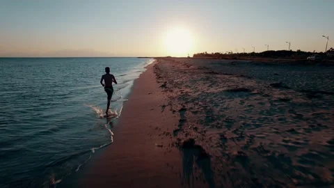Drone view of boy running on the beach during sunset. Stock Footage 161084384