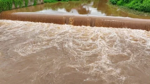 Drone view of brown floodwaters overflowing a barrier. Stock Footage 310707580
