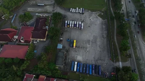 Drone view of a bus parking lot with various vehicles and surrounding greenery Stock Footage 312914077