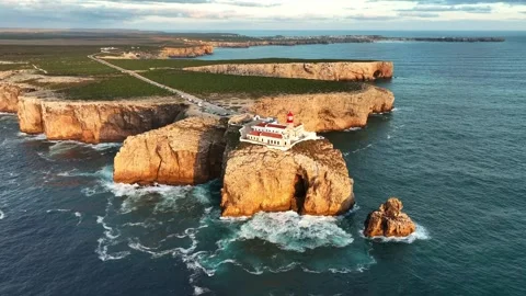 Drone view of Cabo de Sao Vicente lighthouse at sunset above stone cliffs Stock Footage 344288470