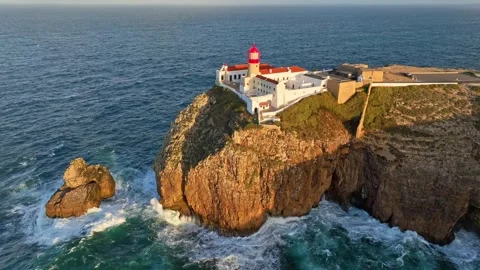 Drone view of Cabo de Sao Vicente Lighthouse at sunrise above a rock stack Stock Footage 344956744
