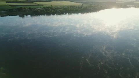 Drone view of calm lake reflecting clouds and sunlight at sunrise 스톡 동영상 319346992