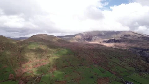 Drone view captures green hills and mountains under a cloudy sky of Snowdonia Stock Footage 320799729