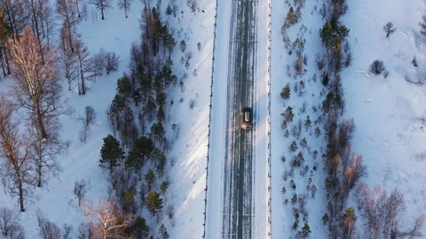 Drone view capturing snow-covered road in winter forest landscape Stock Footage 309895412