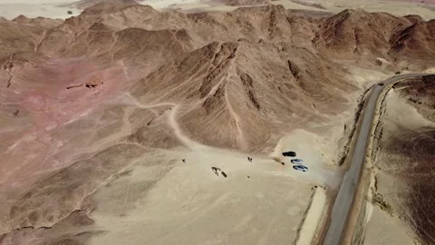 Drone view of a car driving on a winding road through arid badlands. Stock Footage 153469378