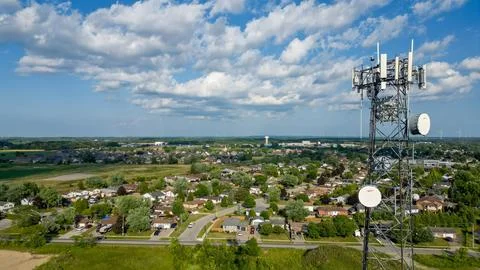 Drone view of cell tower overlooking suburban neighborhood and farmland Stock Photos