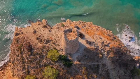 Drone view of a coastal tower on a rocky shore near the sea in the afternoon Видео 342788447