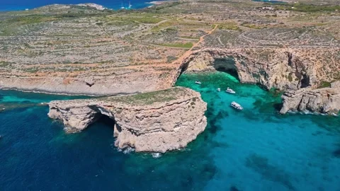 Drone view of Comino Malta with turquoise water, cliffs and boats below Video stock 340588751