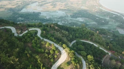 Drone View of Curved Road Snaking Down Hillside Facing Coastal Bay in Sukabumi Stock Footage 344365039