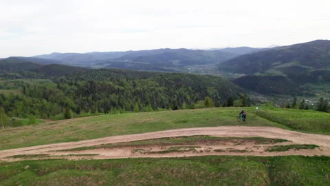 Drone view cyclist riding e-bike through forested slope in Carpathian Mountains Stock Footage 346545673
