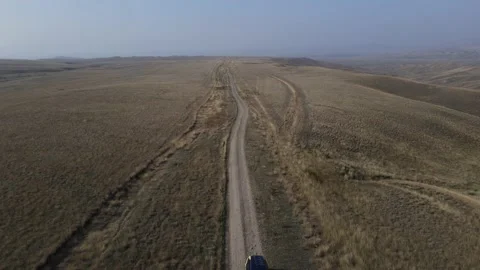Drone view of the desert road with lots of dust and a car driving on it, 4k Stock Footage 168472744