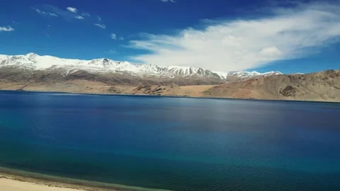 Drone view of dramatic mountain shadows dancing over the calm waters of Tso Stock Footage 310806942