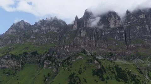 Drone View of Dramatic Swiss Cliffs with Low Clouds and Green Slopes Stock Footage 340629850